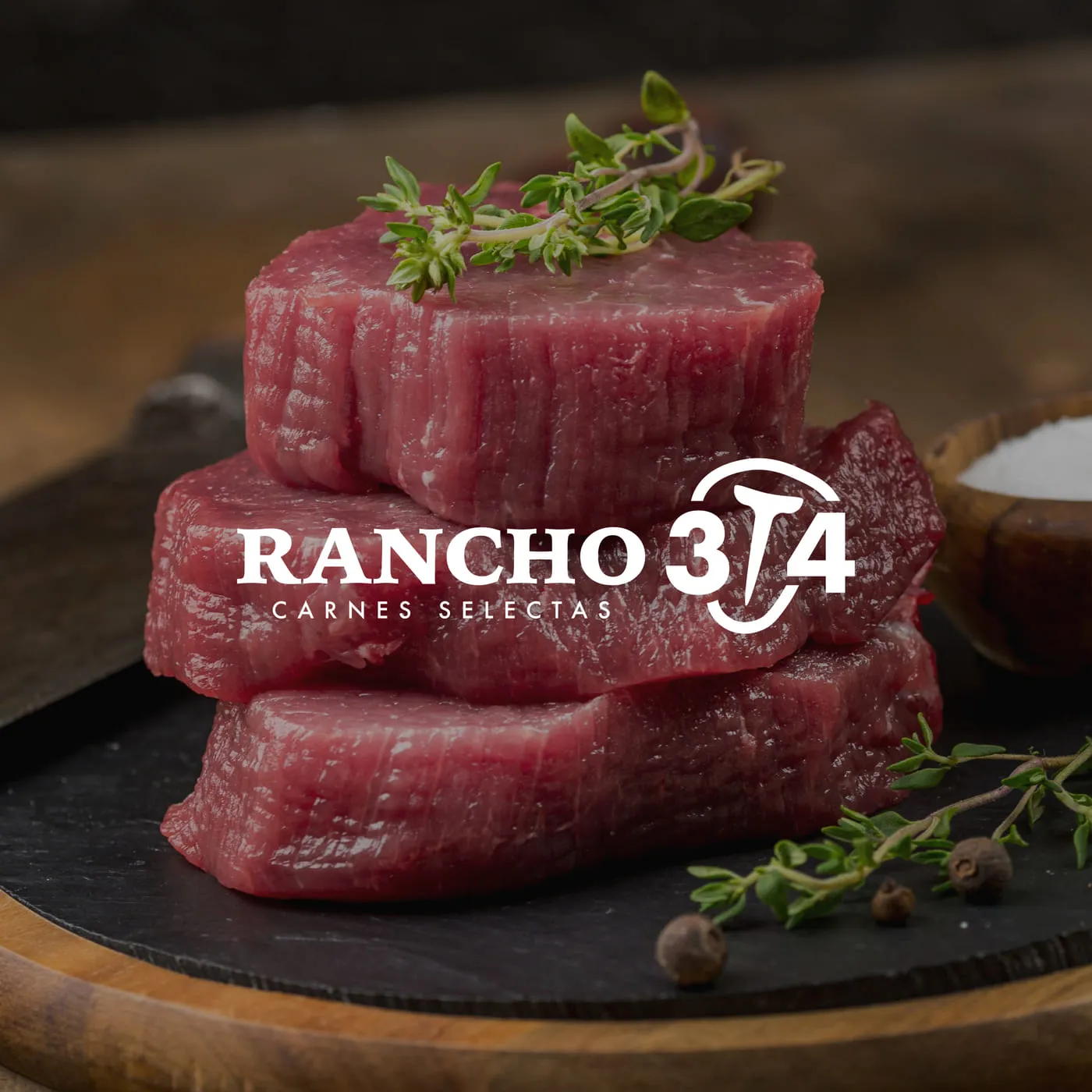Cortes de carne apilados sobre pizarra con la marca Rancho 3/4 Carnes Selectas